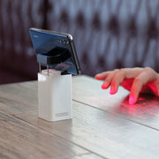 Virtual Laser Keyboard Bluetooth Wireless Projector in use, projecting a keyboard onto a table with a smartphone.